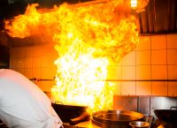 A bright fire on a frying pan in a professional kitchen